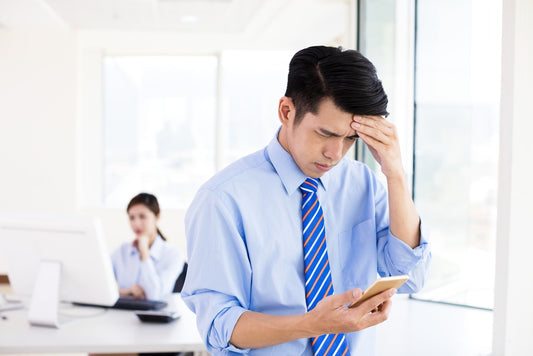 Man experiencing digital eye strain and a headache from using a smartphone