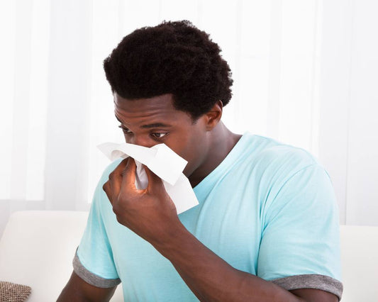 Man with sinus pain blowing his nose